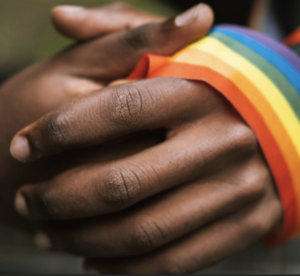 prayerful hands holding rainbow flag